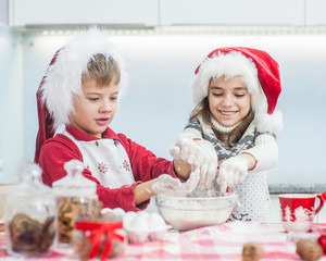 children in Christmas hats prepare cookies in the kitchen
