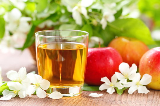 Sweet apple juice, apples and flowers on the table
