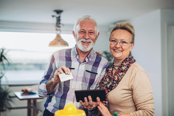 Senior couple using digital tablet in the kitchen at home for online shopping