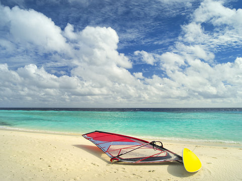 wind surfing board on the sand beach in front of emerald sea on Maldives island in sun shining day
