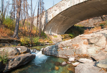 Fototapeta na wymiar STONE BRIDGE OVER BARING CREEK ON THE GOING TO THE SUN ROAD IN GLACIER NATIONAL PARK IN MONTANA UNITED STATES