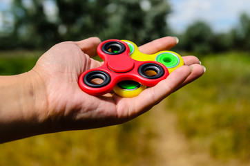 Red and yellow fidget spinners in female hand