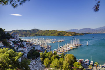 Fototapeta premium Turkey, Fethiye, view of the harbor with numerous yachts, and beautiful mountains in the background in the rays of the sun