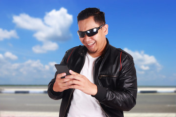 Young Man Texting Reading Chatting on His Phone Happy Smiling Gesture