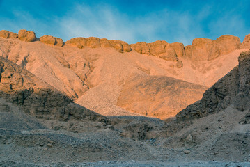 Fototapeta premium Desert hillside with stones in the Valley of the Kings in Egypt with a blue sky and a few clouds