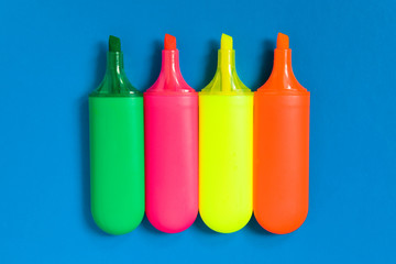 Multicolored markers lie on a blue sheet of paper.