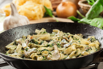 Tagliatelle pasta with spinach and mushrooms on a pan.
