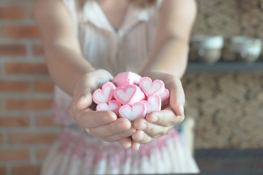 Close-up heart shape of pink marshmallow in woman hand. Concept for valentines day celebration or couple of love