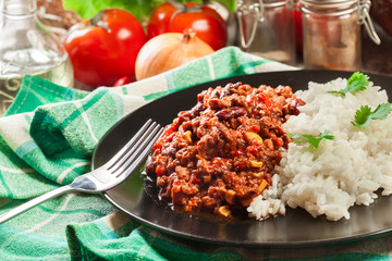 Hot chili con carne with ground beef, beans, tomatoes and corn served with rice
