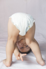Fototapeta na wymiar cheerful kid in diapers looks between the legs