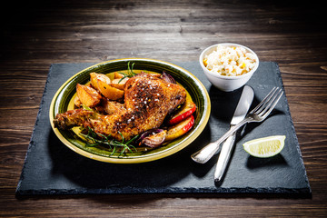 Roast chicken leg with chips on wooden background