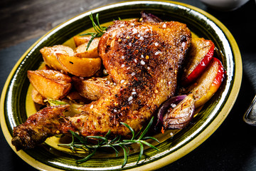 Roast chicken leg with chips on wooden background