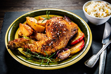 Roast chicken leg with chips on wooden background