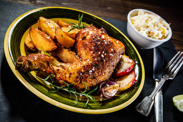 Roast chicken leg with chips on wooden background