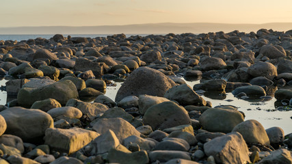 Obraz premium The stones of Llantwit Major Beach in the evening sun, South Glamorgan, Wales, UK