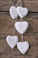 group of little white wooden hearts hanging  on a rustic plank 