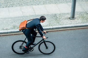 High angle view of young man wearing business suit while riding an utility bicycle on the street