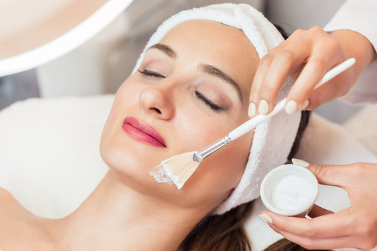 Close-up of the face of a beautiful woman relaxing during facial treatment with moisturizing cream for sensitive skin in a modern beauty center