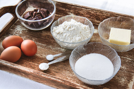 Baking ingredients for chocolate cake muffins or cookies lying ready on wooden kitchen tray. Mise en place, white background, measured ingredients.