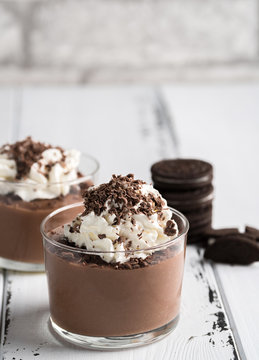 Chocolate mousse in a glasses on a white wood background.