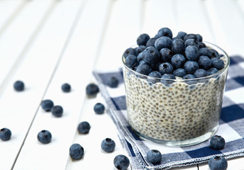 Chia pudding with blueberries on striped canvas, white wood background
