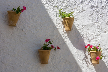 Fototapeta na wymiar Olvera is a white village in Cadiz province, Andalucia, Southern Spain - typical vases hanging on the wall with carnations