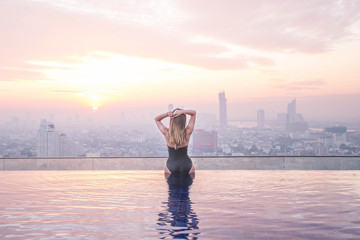 Fototapeta na wymiar Sexy girl enjoing the sunrise city view from the root top. Thailang, Bangkok.