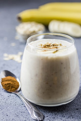 Paleo coconut milk banana oat smoothie in glass on concrete background. Selective focus, space for text. 