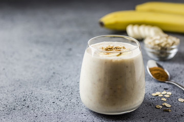 Cinnamon bun banana oat smoothie in glass on concrete background. Selective focus, space for text. 