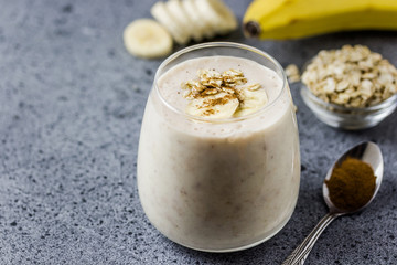 Healthy coffee banana oat smoothie in glass on concrete background. Selective focus, space for text. 