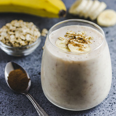 Overnight oat banana smoothie in glass on concrete background. Selective focus, space for text. 