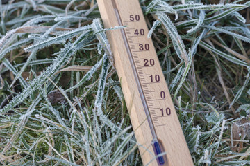 Thermometer aus Holz im gefrorenen Gras bei kalten Temperaturen