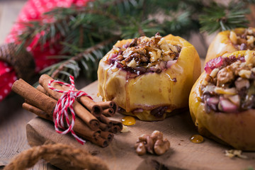Baked apples stuffed with berries, walnuts and honey on a wooden cutting board.