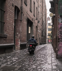 Motor cyclist travelling down a narrow alley way