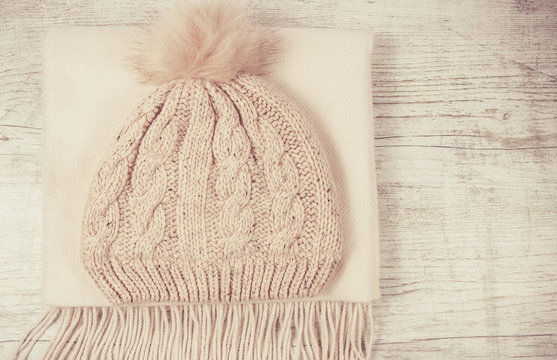Warm winter knitted clothes - hat, scarf, on a wooden background.