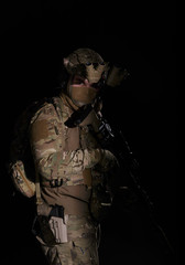 Obraz na płótnie Canvas Army soldier in Combat Uniform with assault rifle, combat helmet and night vision device. Studio shot, dark background