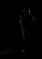 Army soldier in Combat Uniform with assault rifle, combat helmet and night vision device. Studio low-key shot, dark background