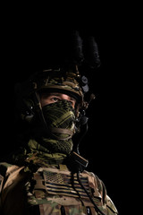 Army soldier in Combat Uniform, combat helmet and night vision device. Studio shot, dark background