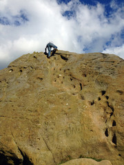 Man climbing a large rock on Ilkley Moor in Yorkshire, England