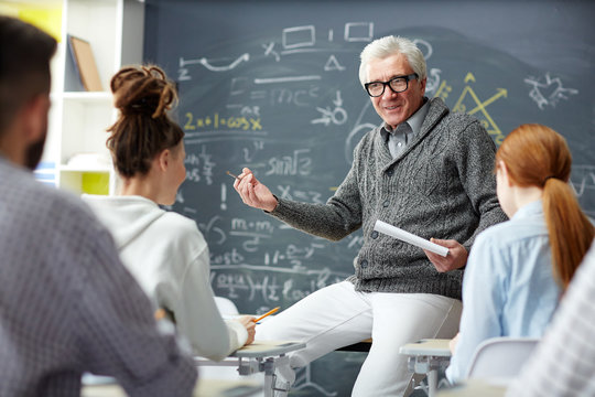 Friendly teacher talking to his students at lesson of algebra or trigonometry