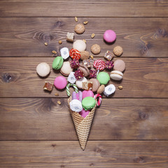 Fototapeta na wymiar Sweets in a waffle cone on wooden background
