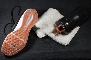 Sneakers, white towel and bottle of water on the floor of gym . Top view