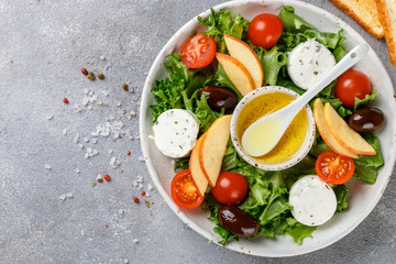 Fresh goat cheese salad with lettuce, cherry tomatoes, Apple, Kalamata olives and a dressing of olive oil. Copy space top view