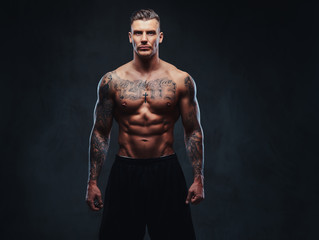 Fototapeta na wymiar A muscular tattooed man on a dark background.
