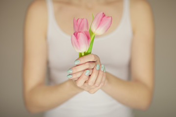 woman hands with perfect nail art holding pink spring flowers tulips, sensual studio shot can be used as background