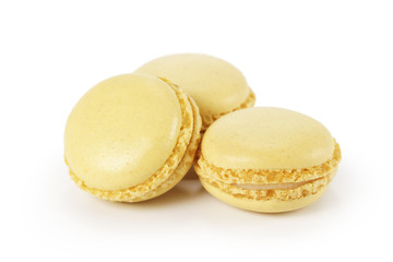 three yellow lemon macarons isolated on white