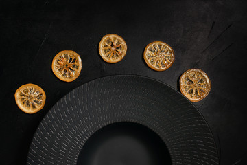 Decorative plate on black background decorated with dried citrus. Unique art crockery. Luxury style concept