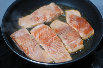  large steak of salmon is fried in sunflower oil.