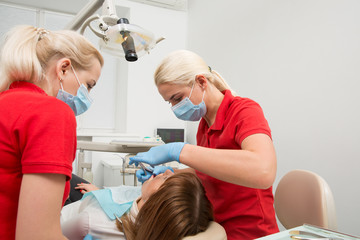 Medical dentist team in dental office with female patient preparing for treatment. dentist and assistent in process