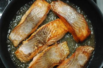  large steak of salmon is fried in sunflower oil.